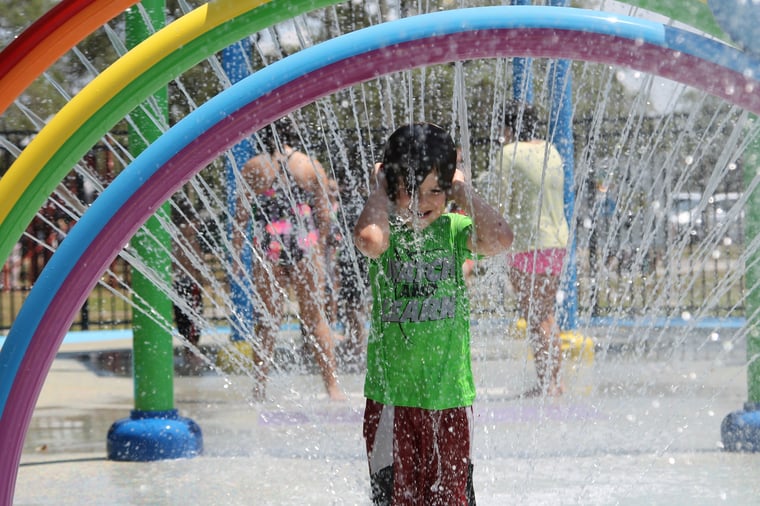 patron enjoying water play area with multi-colored spraying rings