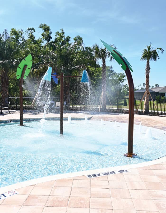 misting leaf-themed water features and dumping buckets in a beach-entry swimming pool