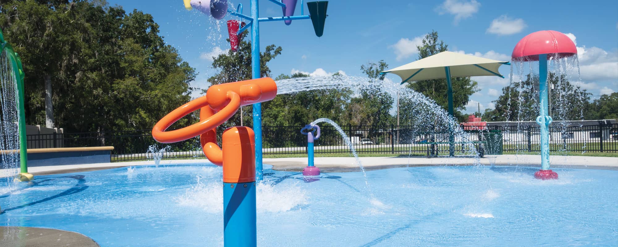 orange and blue water cannon on an inclusive splash pad design with interactive water features