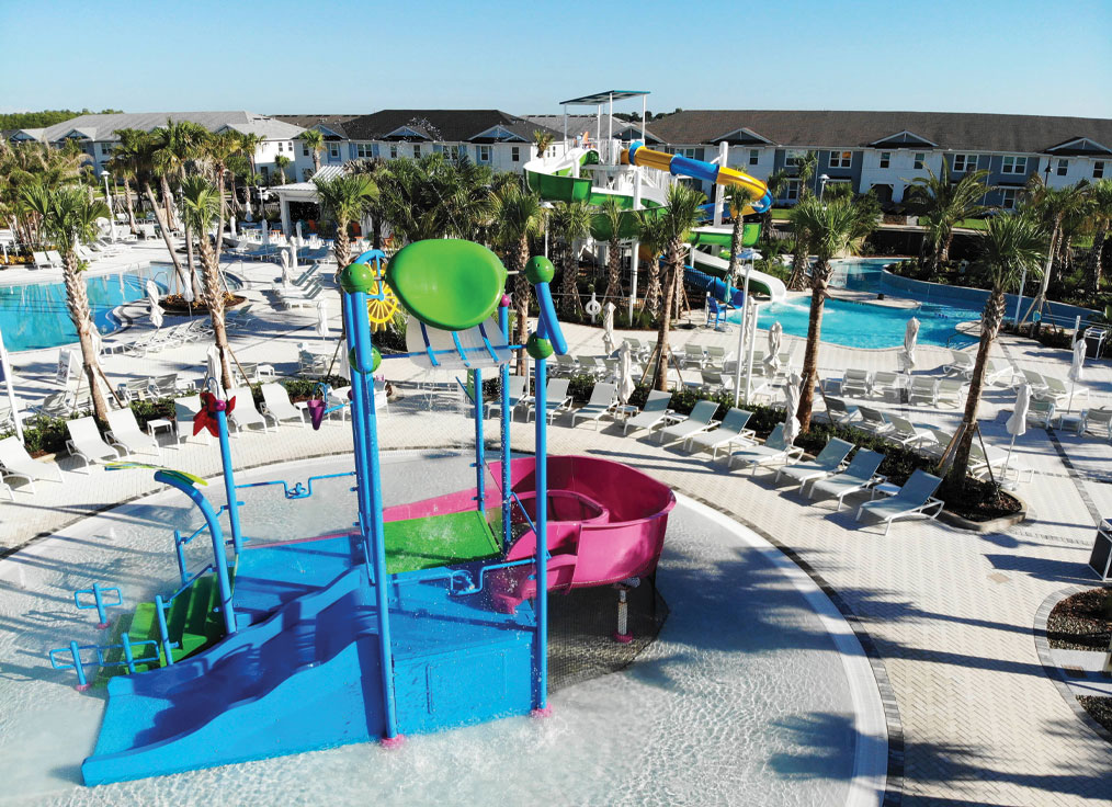 overhead view of a waterpark with a water playset, double flume waterslide tower, and lazy river