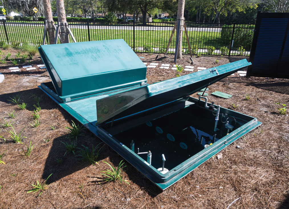 dual lid subterranean collector tank in a grassy area