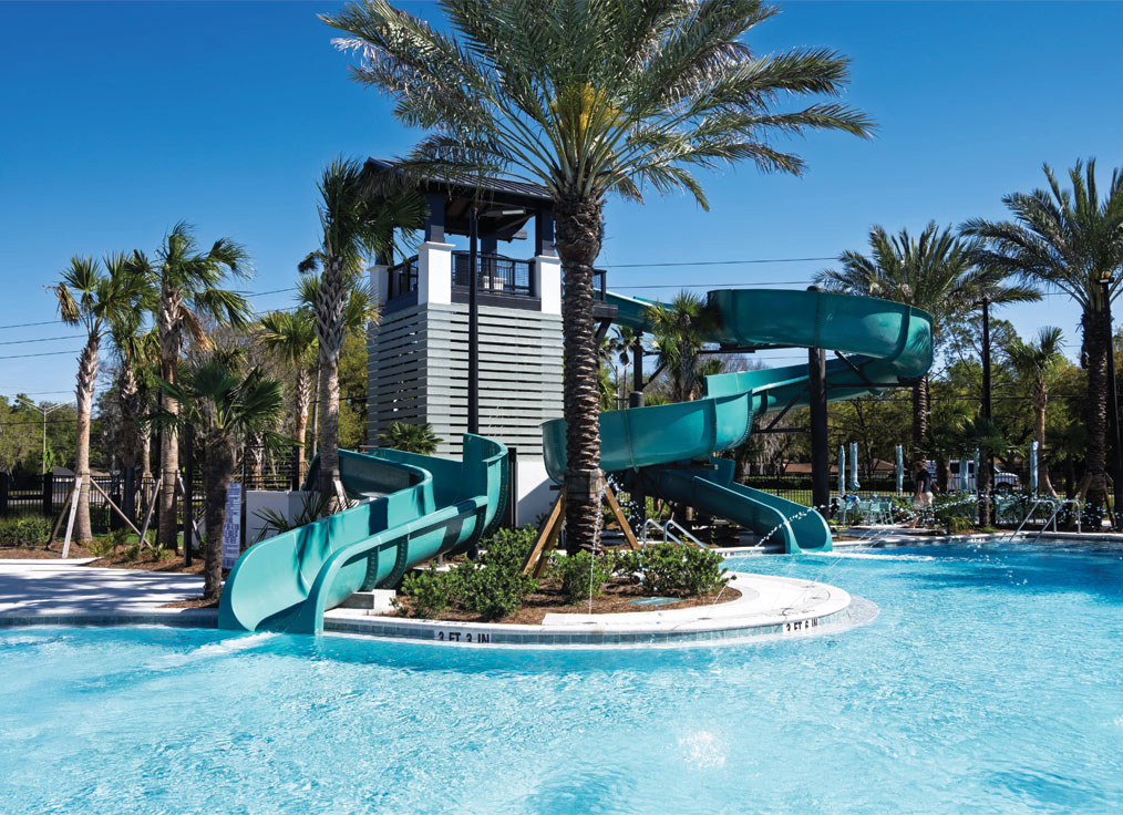 a small blue waterslide and a large blue waterslide pictured in a tropical setting with a large modern tower in the background