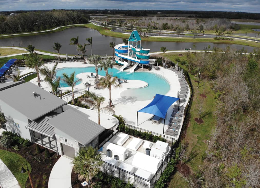 overhead view of a swimming pool with a double flume waterslide tower and white swimming pool recirculating filtration equipment packs