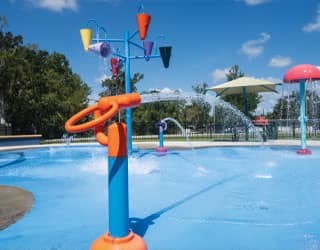 orange and blue water cannon on an inclusive splash pad design with interactive water features