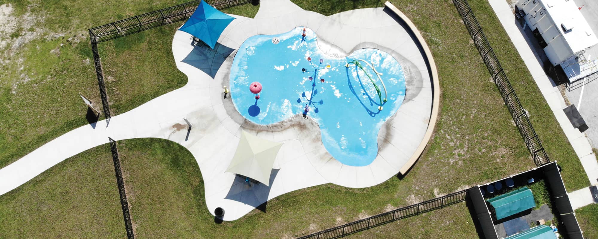overhead view of splash pad package design with green recirculating filtration system equipment in an gated equipment yard