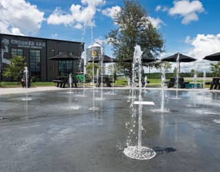 fountain in a cans and cone shaped ground sprays make up the splash pad design