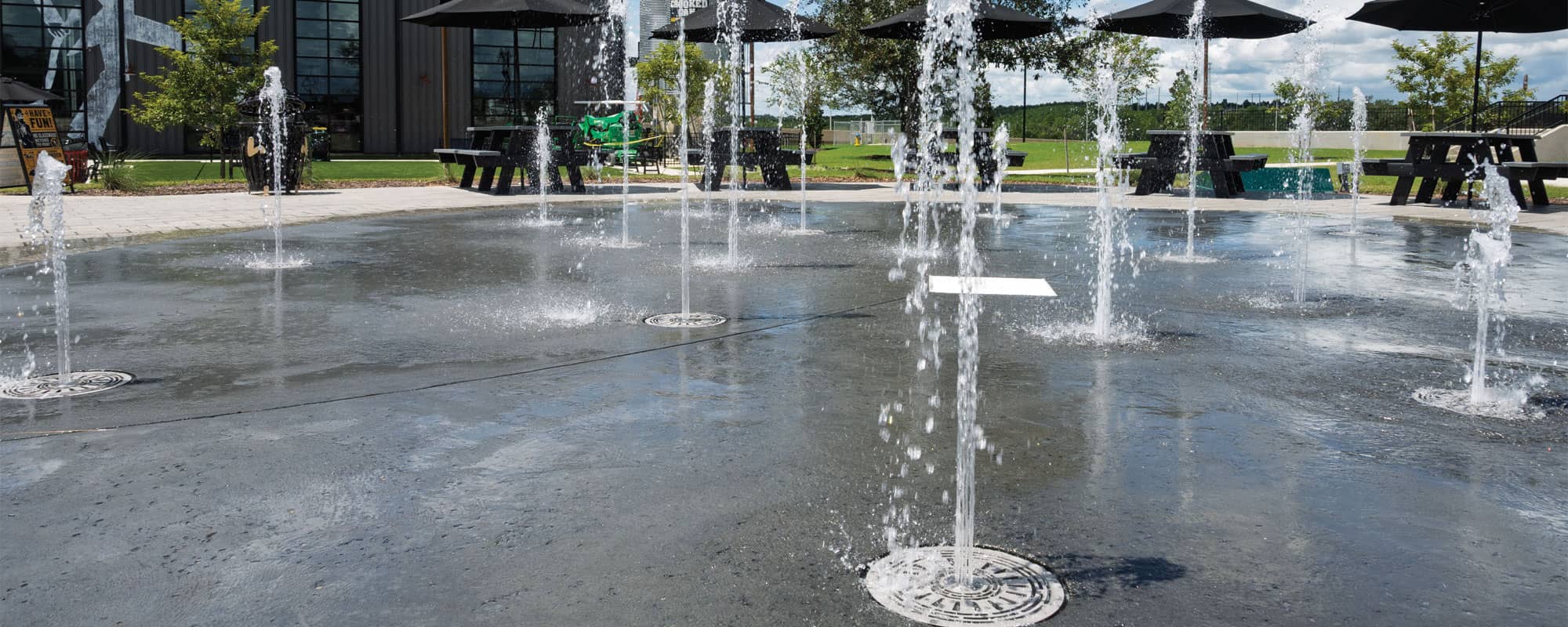 fountain in a cans and cone shaped ground sprays make up the splash pad design