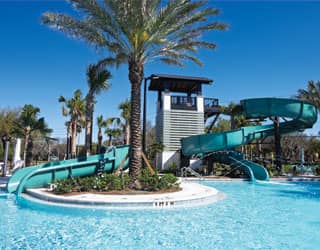 swimming pool with a small and large blue waterslide in a tropical setting