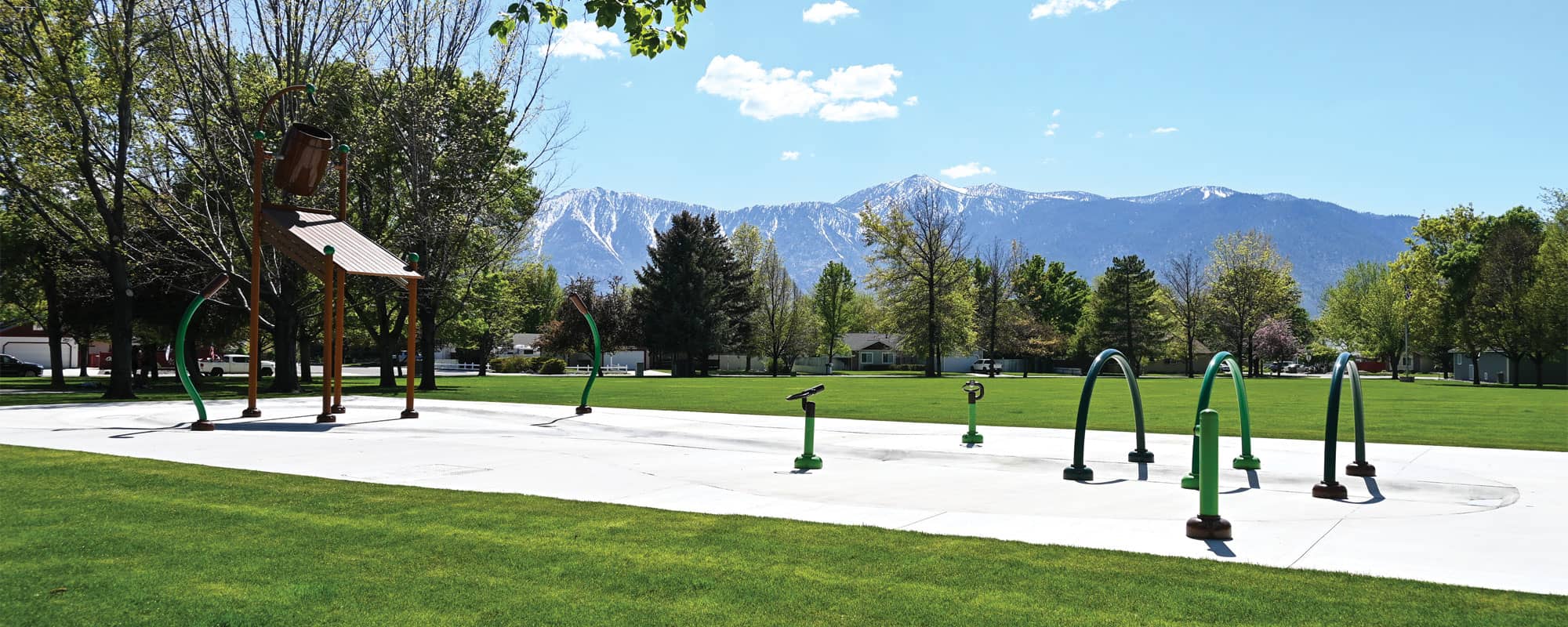 splash pad with brown and green water features that creates a nature-themed aquatic play space