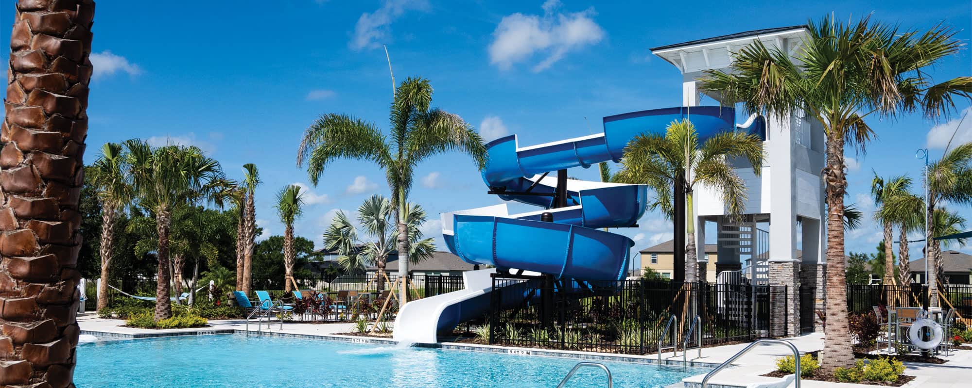 blue waterslide on the deck of a swimming pool in a tropical landscape