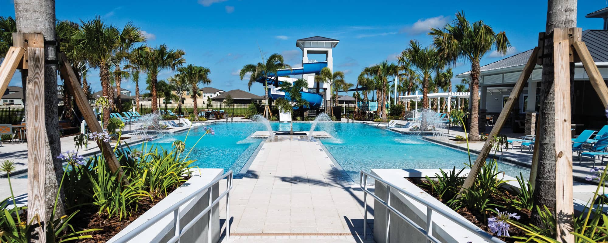 entrance to a swimming pool that features pool deck jets and an open flume waterslide