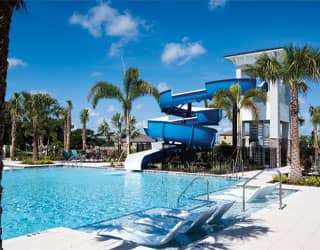 blue waterslide on the deck of a swimming pool in a tropical landscape