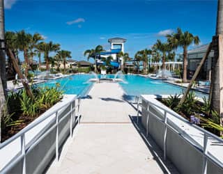entrance to a swimming pool that features pool deck jets and an open flume waterslide