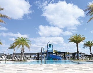 resort-style swimming pool with a multi-level water playset in a tropical environment