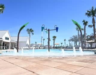 palm tree-themed interactive water features and dumping buckets in a beach-entry swimming pool