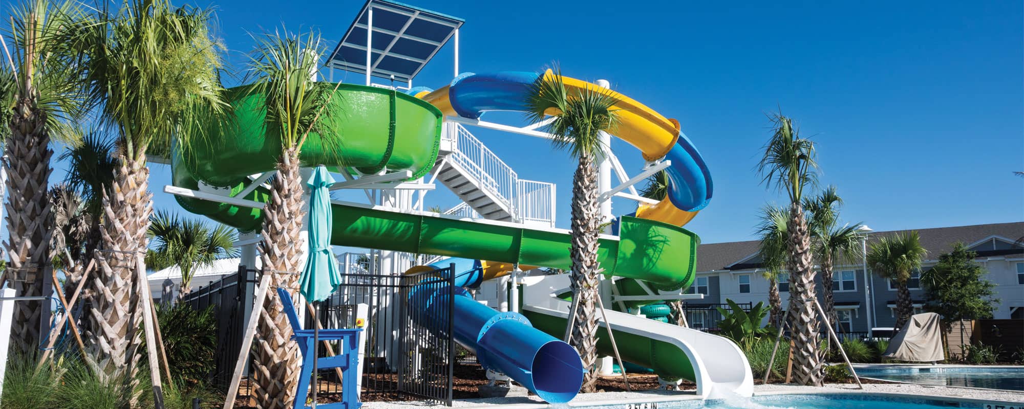 double-flume waterslide structure with a blue and yellow closed flume slide and a green open flume slide