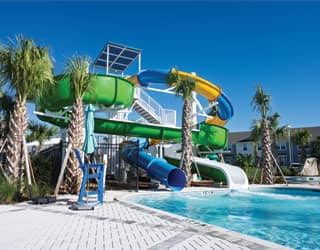 double-flume waterslide structure with a blue and yellow closed flume slide and a green open flume slide